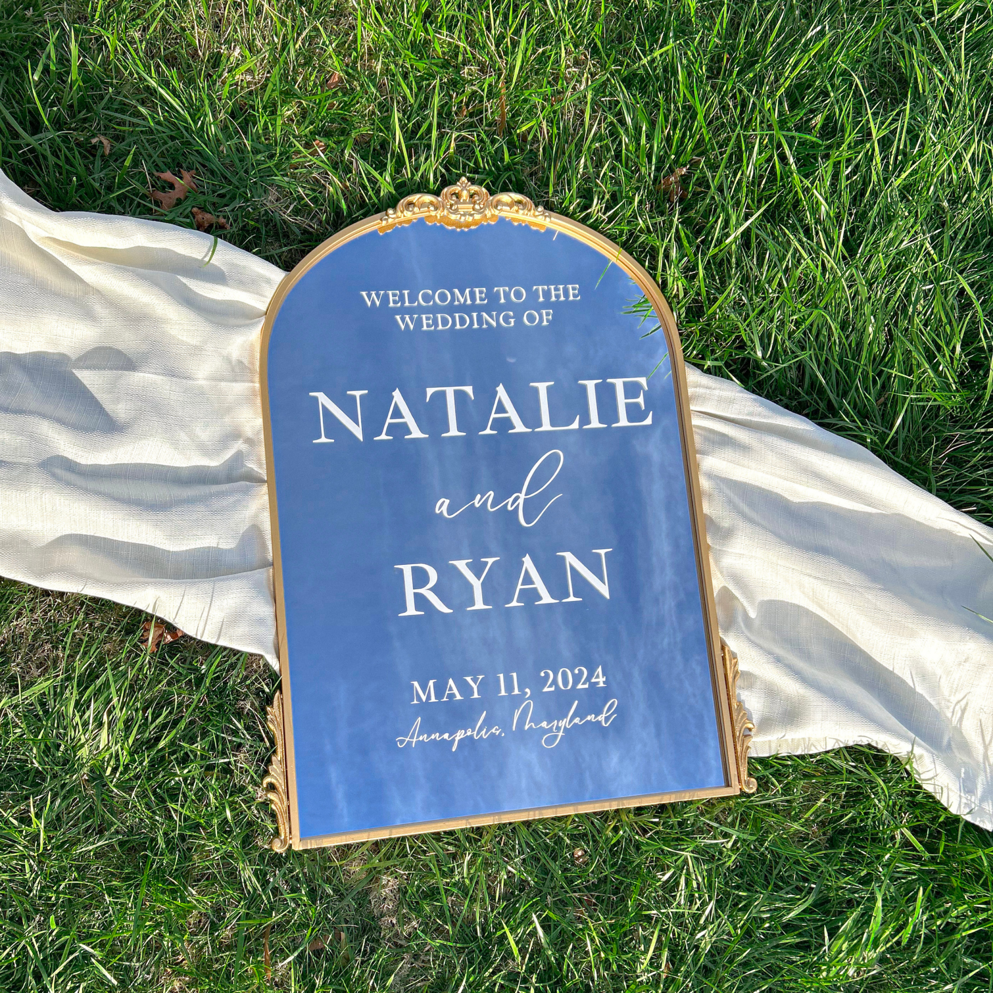 Antique gold arch mirror wedding welcome sign on grass.