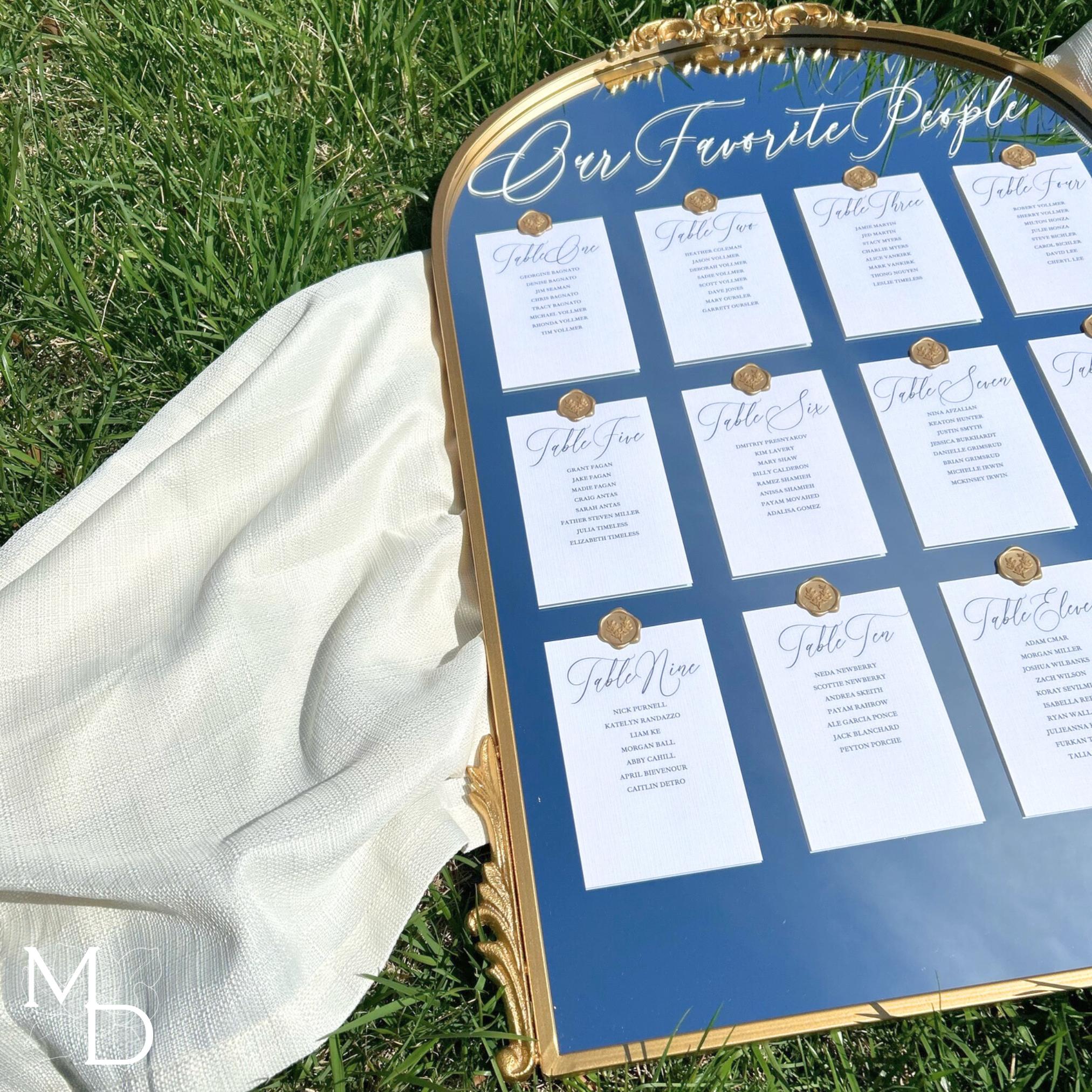 Elegant gold mirror wedding seating chart outdoors with customizable wax seal designs.