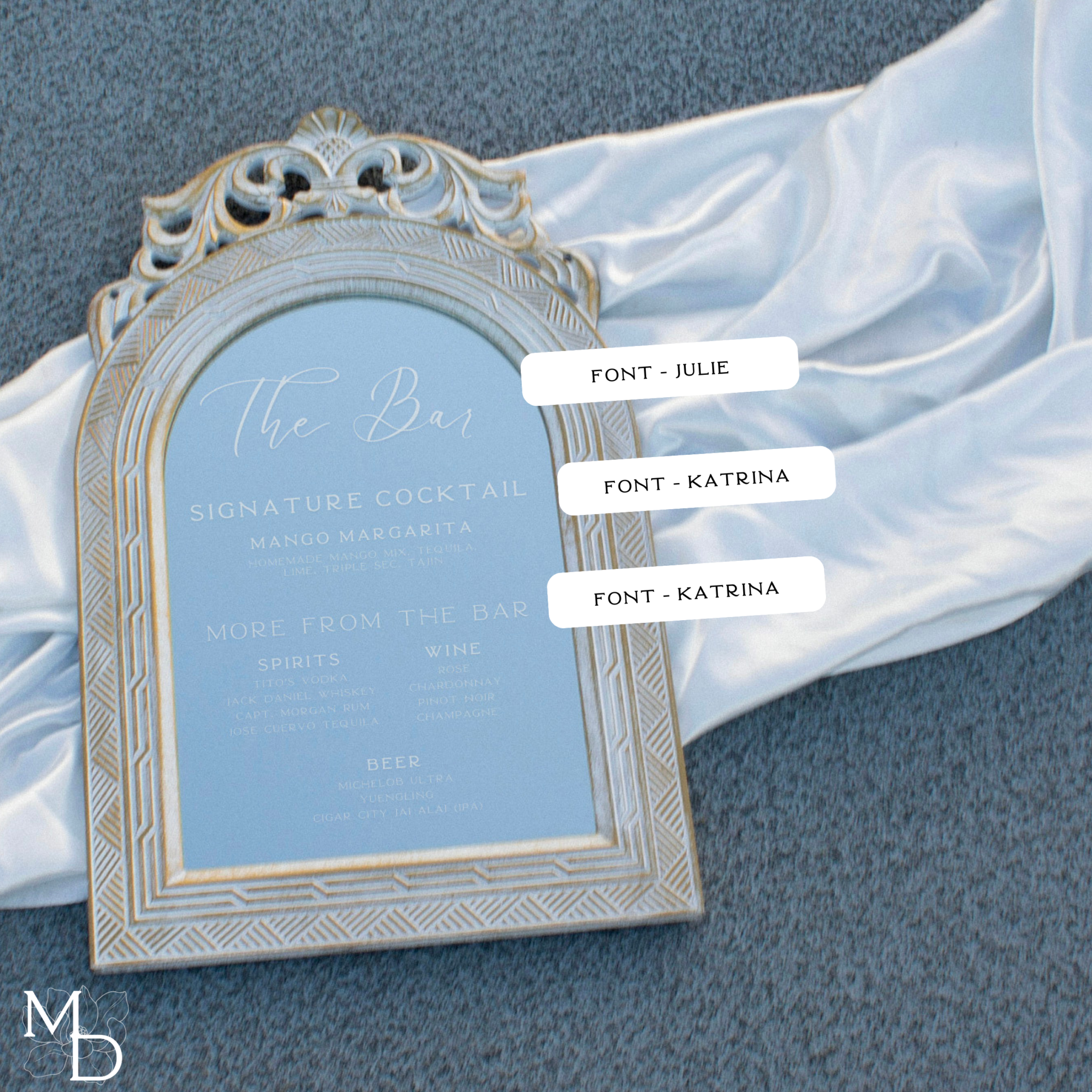 Custom wedding cocktail bar menu list on rustic white mirror with vintage-style wood frame, displaying drink selection elegantly.
