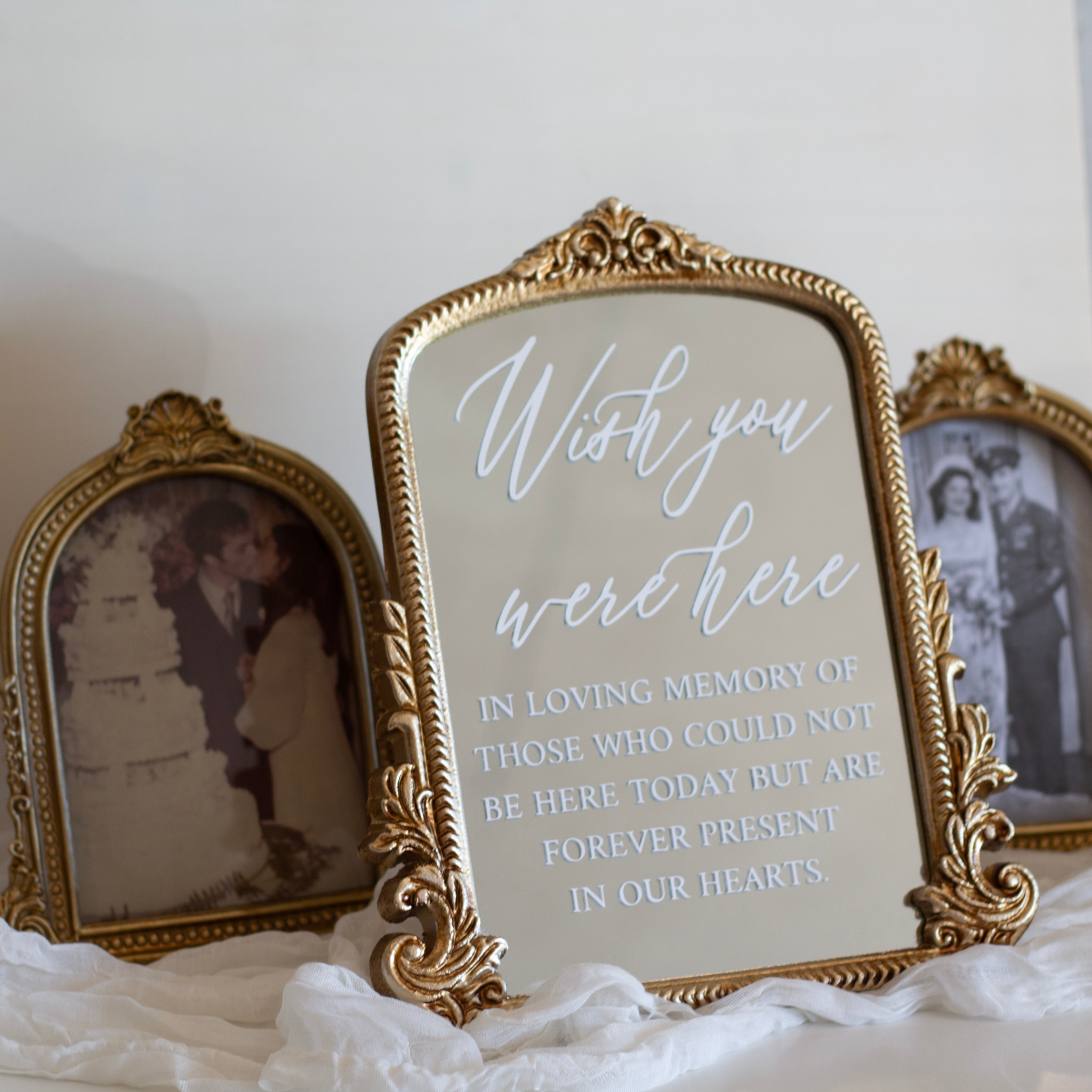 Wedding memorial sign with "Wish You Were Here" message in gold ornate frame, surrounded by vintage photos.
