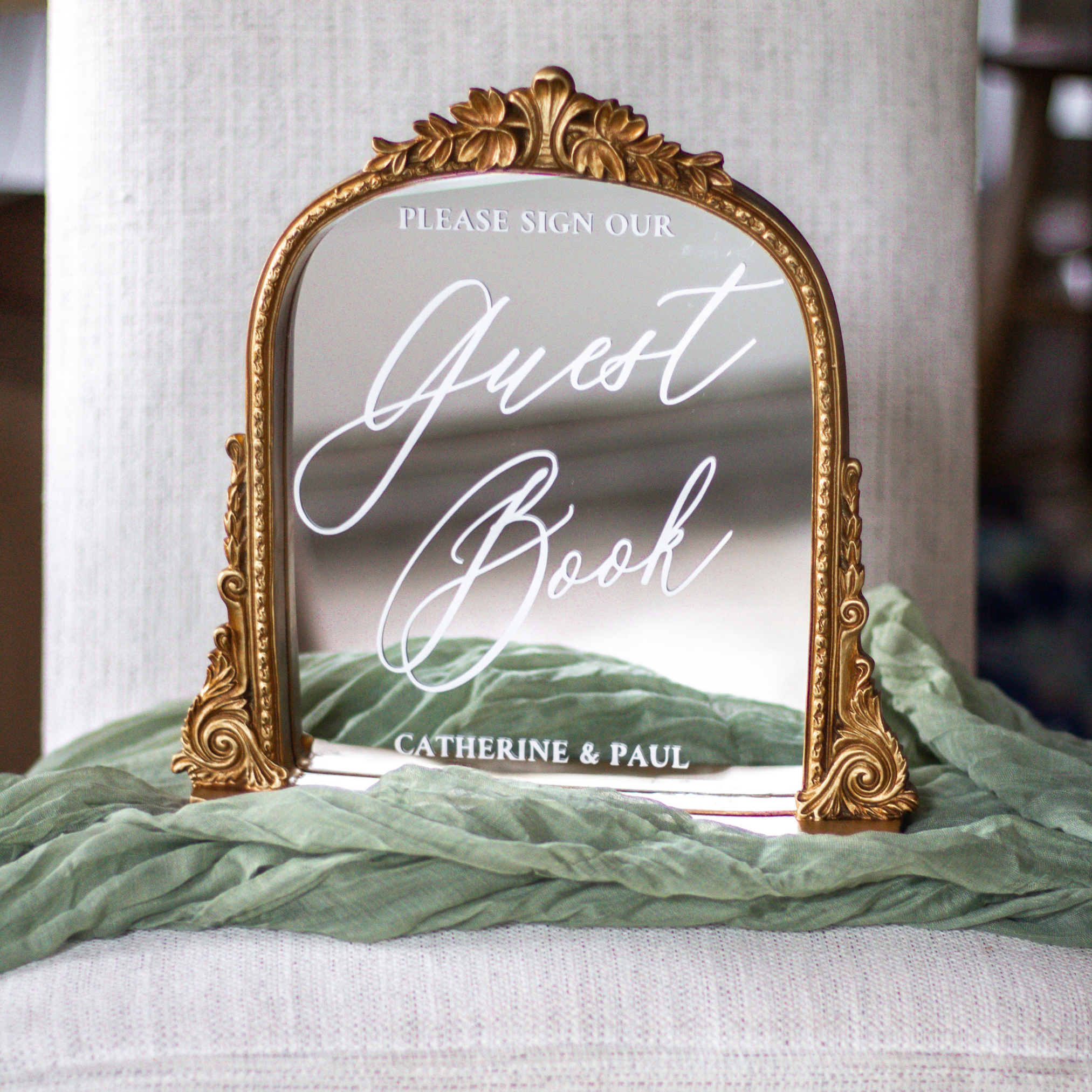Elegant wedding guest book mirror sign with gold frame and calligraphy script at wedding reception.