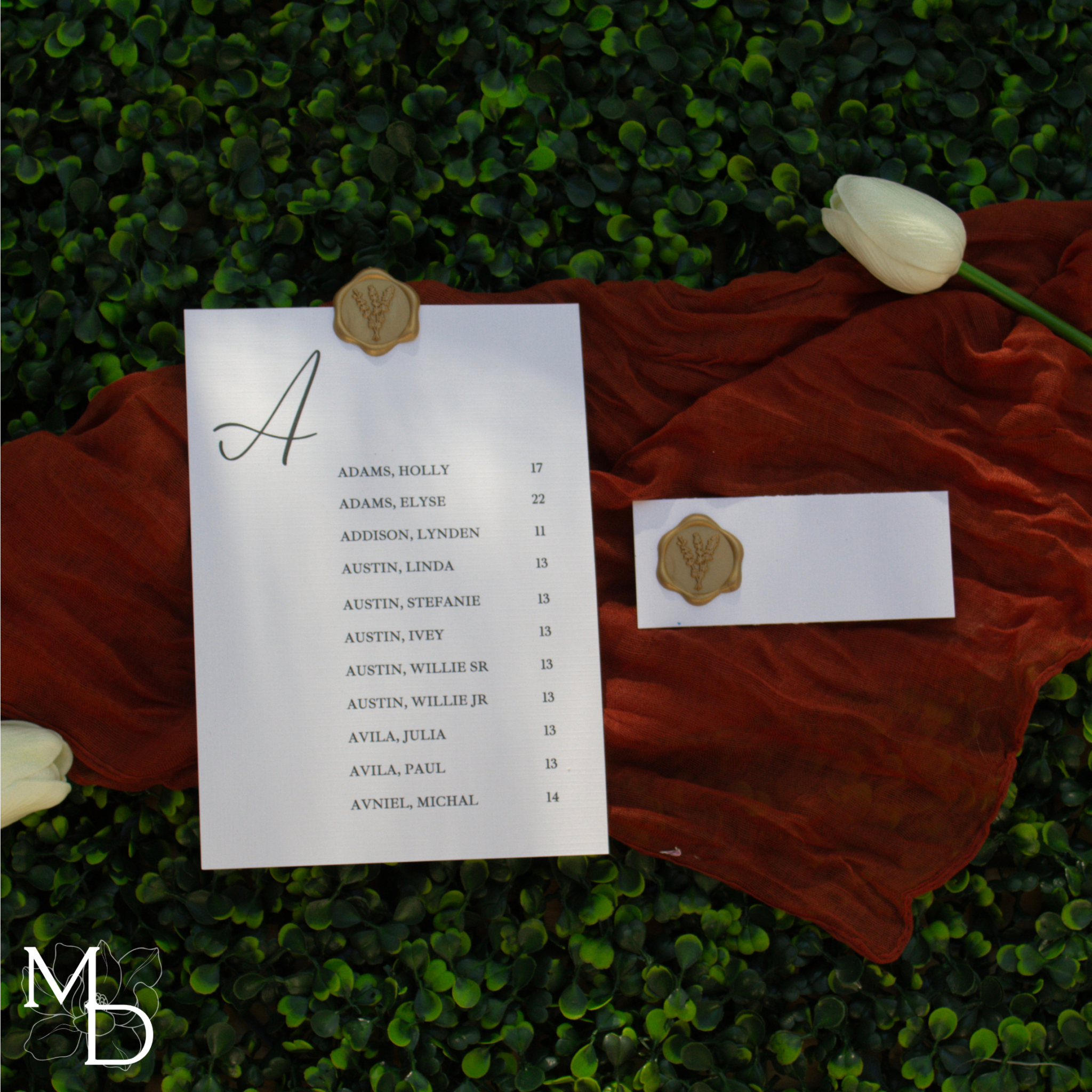 Seating chart assignment cards with elegant linen finish and wax seals on greenery backdrop.