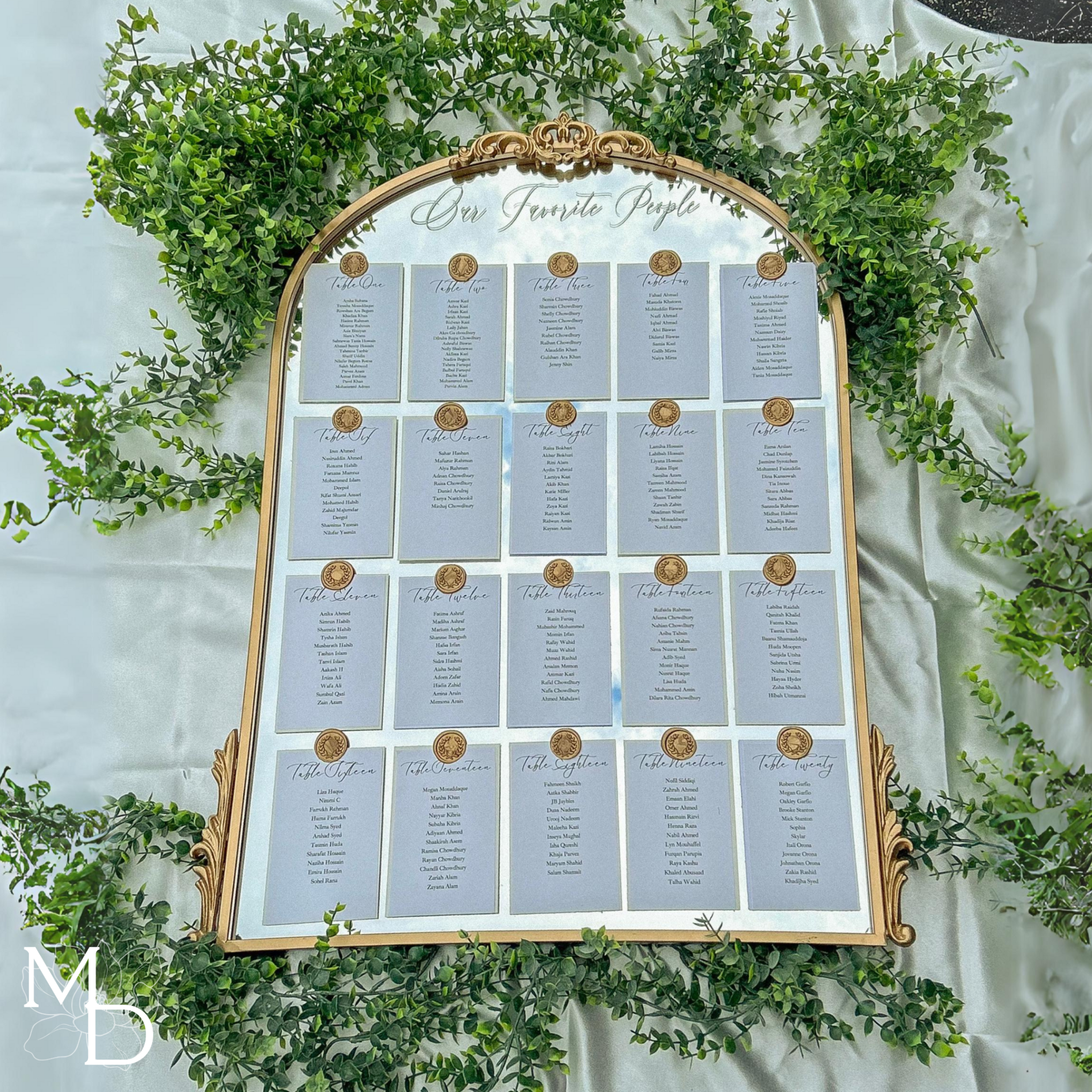 Elegant wedding guest table layout seating chart on arch mirror with gold accents and wax seals.