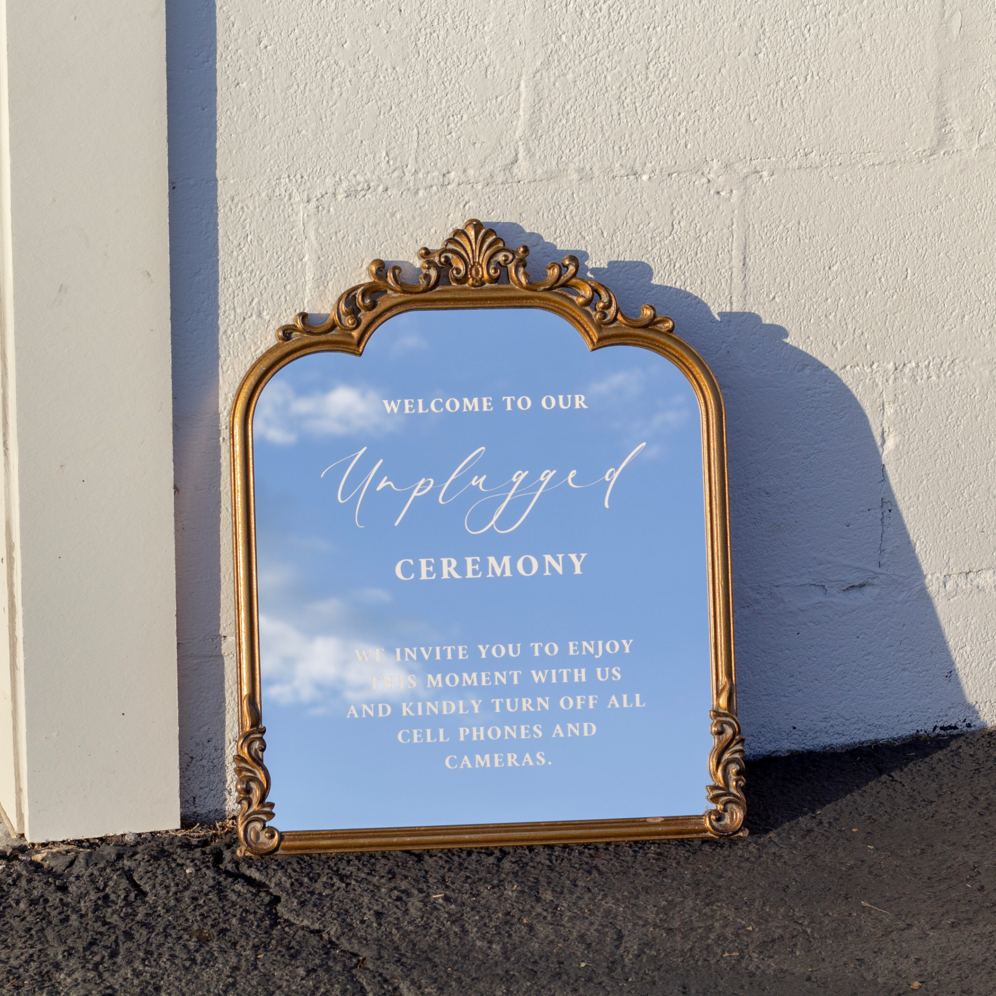 Unplugged Ceremony Sign on decorative wedding mirror outdoors.