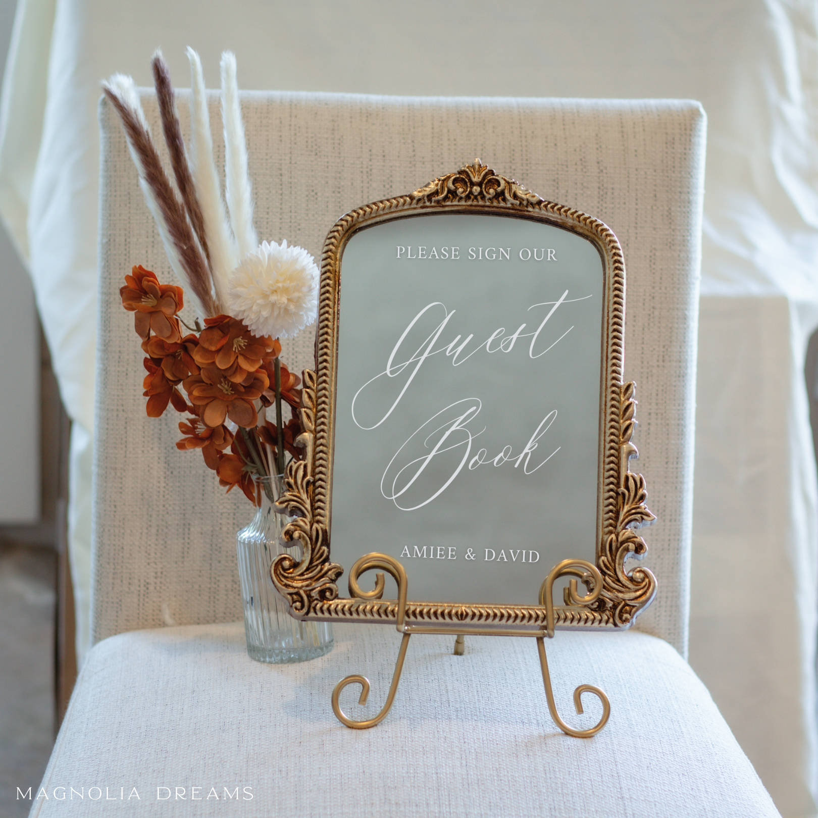 Elegant guest book sign with calligraphy on a gold-framed mirror.