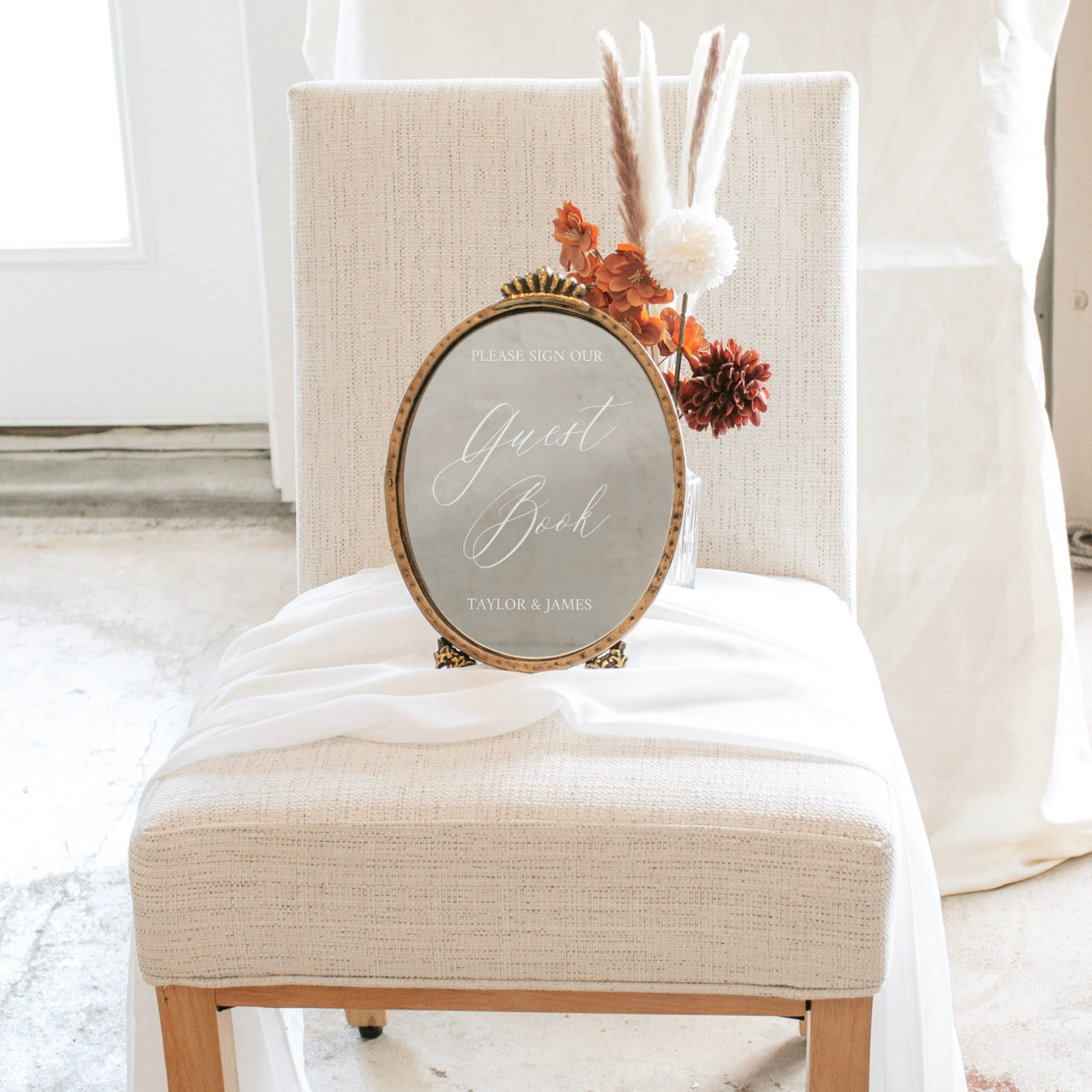 Elegant wedding guest book mirror sign on chair with floral decor.