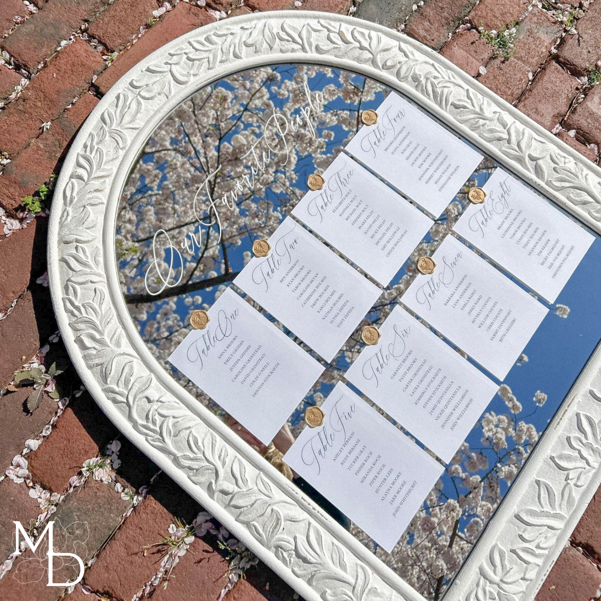 Boho white mirror wedding guest seating chart with elegant card display and gold wax seals.