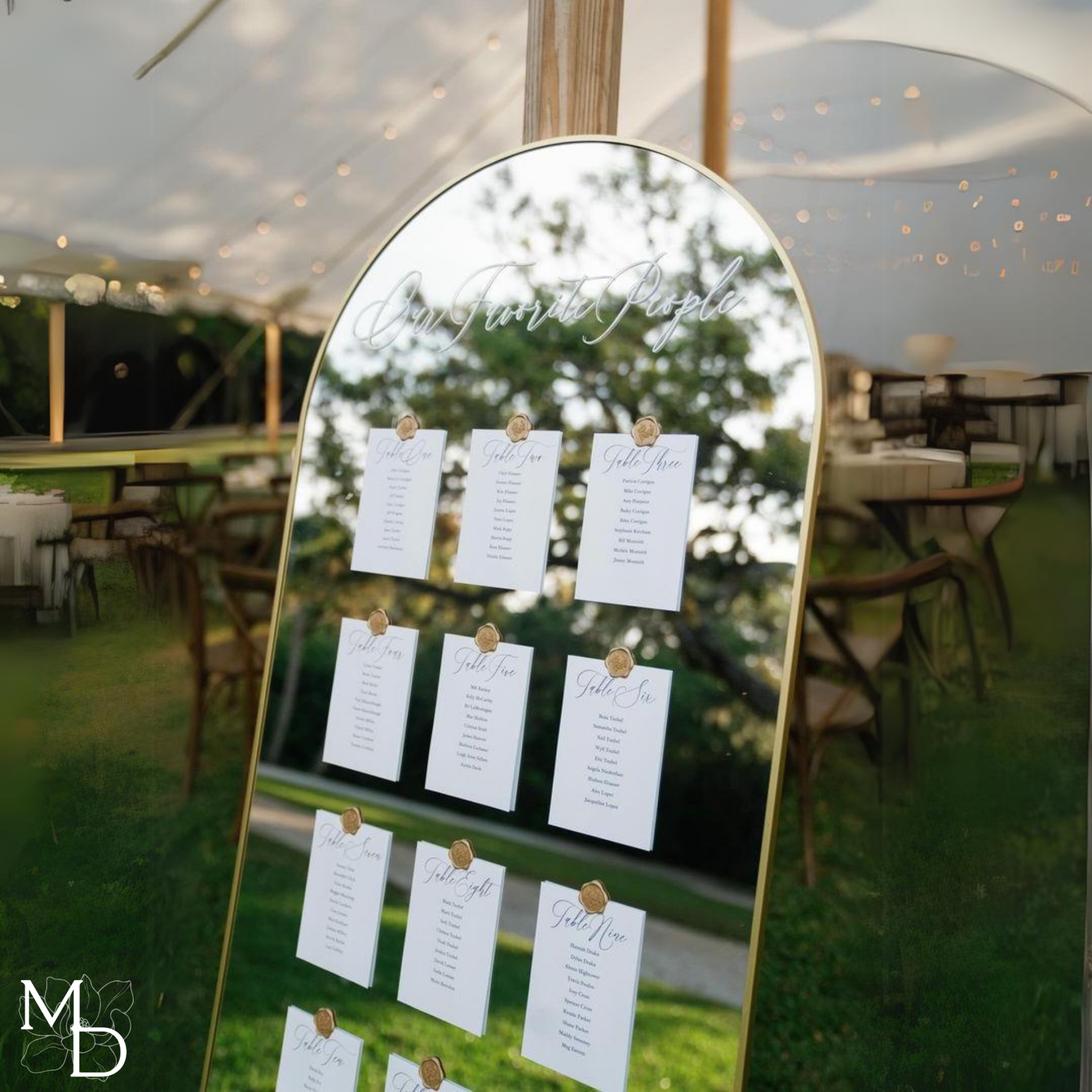 Large gold arch mirror wedding table seating chart with personalized guest names on premium linen cardstock.