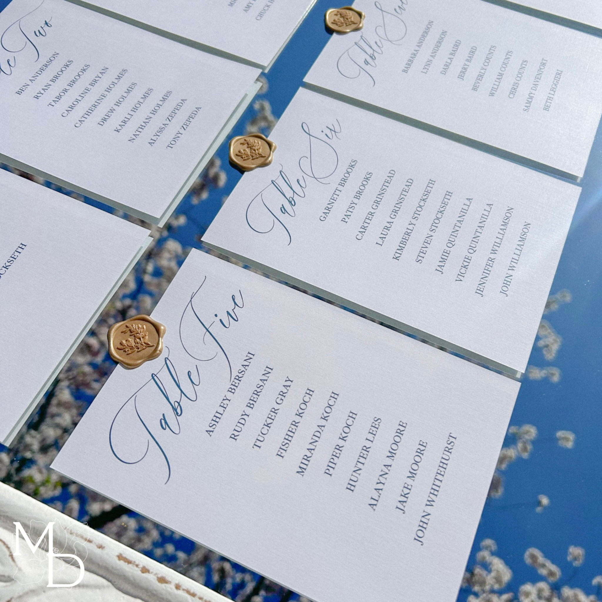 wedding guest seating chart on white mirror with gold wax seal details