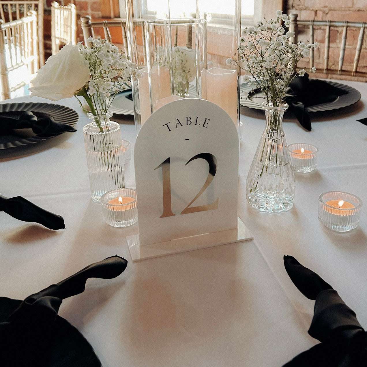 Acrylic table number with gold lettering on white stand for wedding reception.