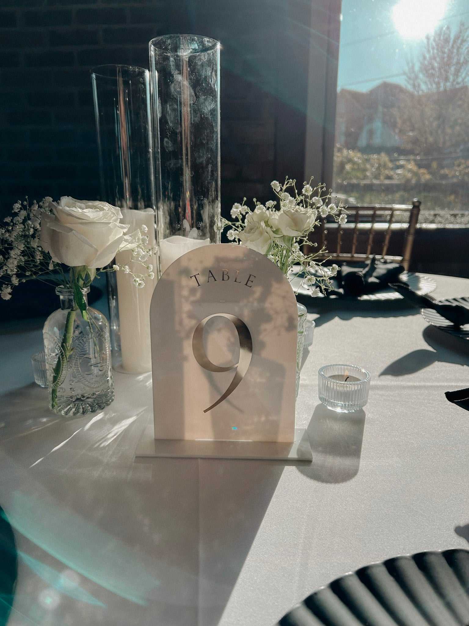 Elegant white acrylic table number with gold lettering and stand for weddings and events.