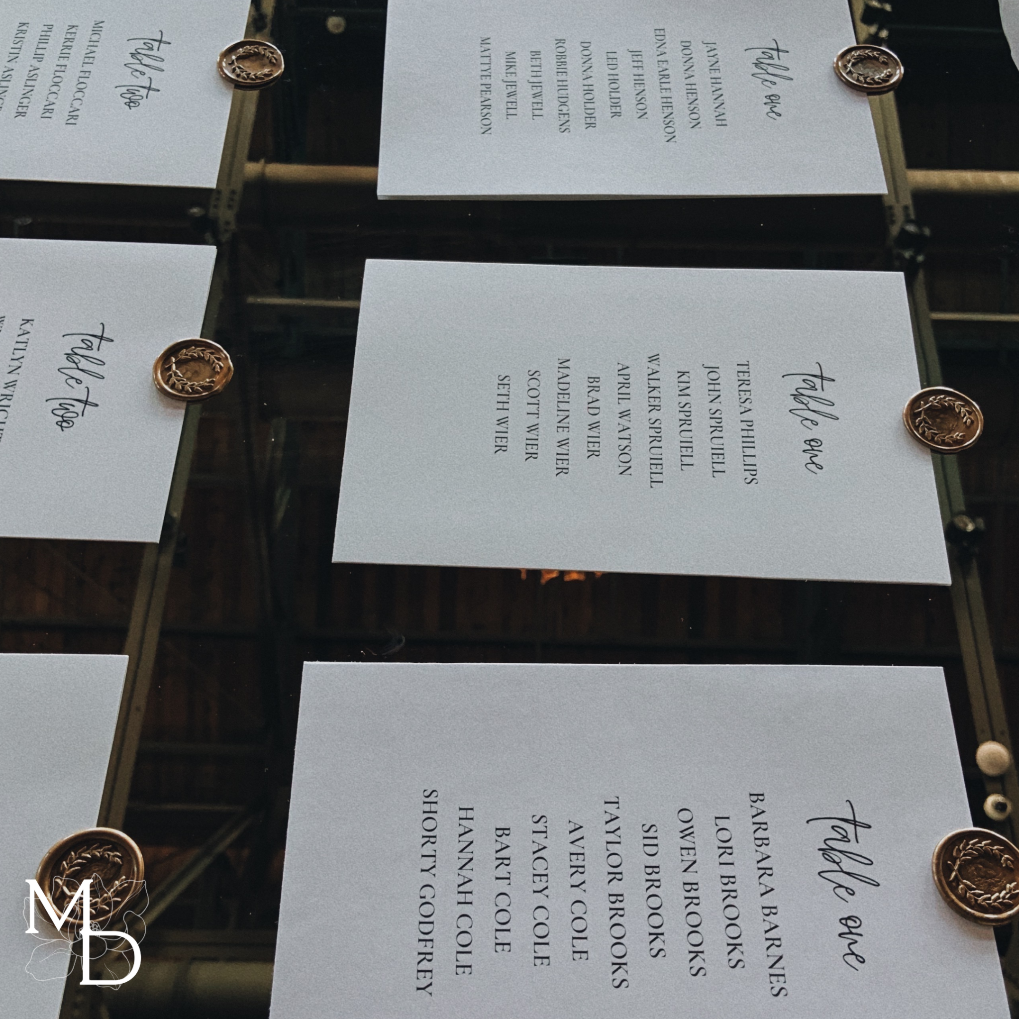 Customized wedding guest seating assignments on large gold mirror with wax seals.