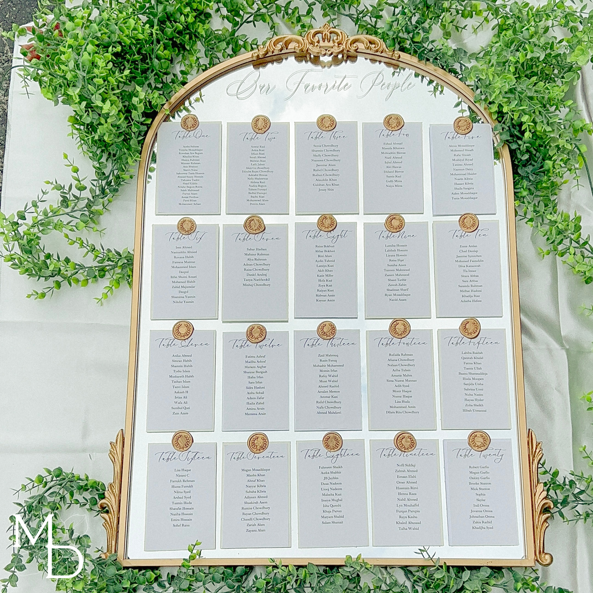 Elegant wedding guest table layout seating chart on arch mirror with gold details.