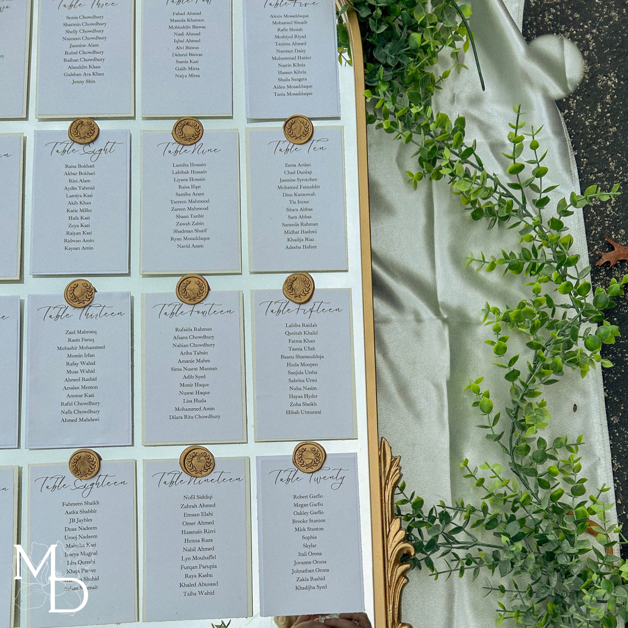 Elegant wedding guest table layout seating chart on gold arch mirror with customizable vinyl decals and wax seals.