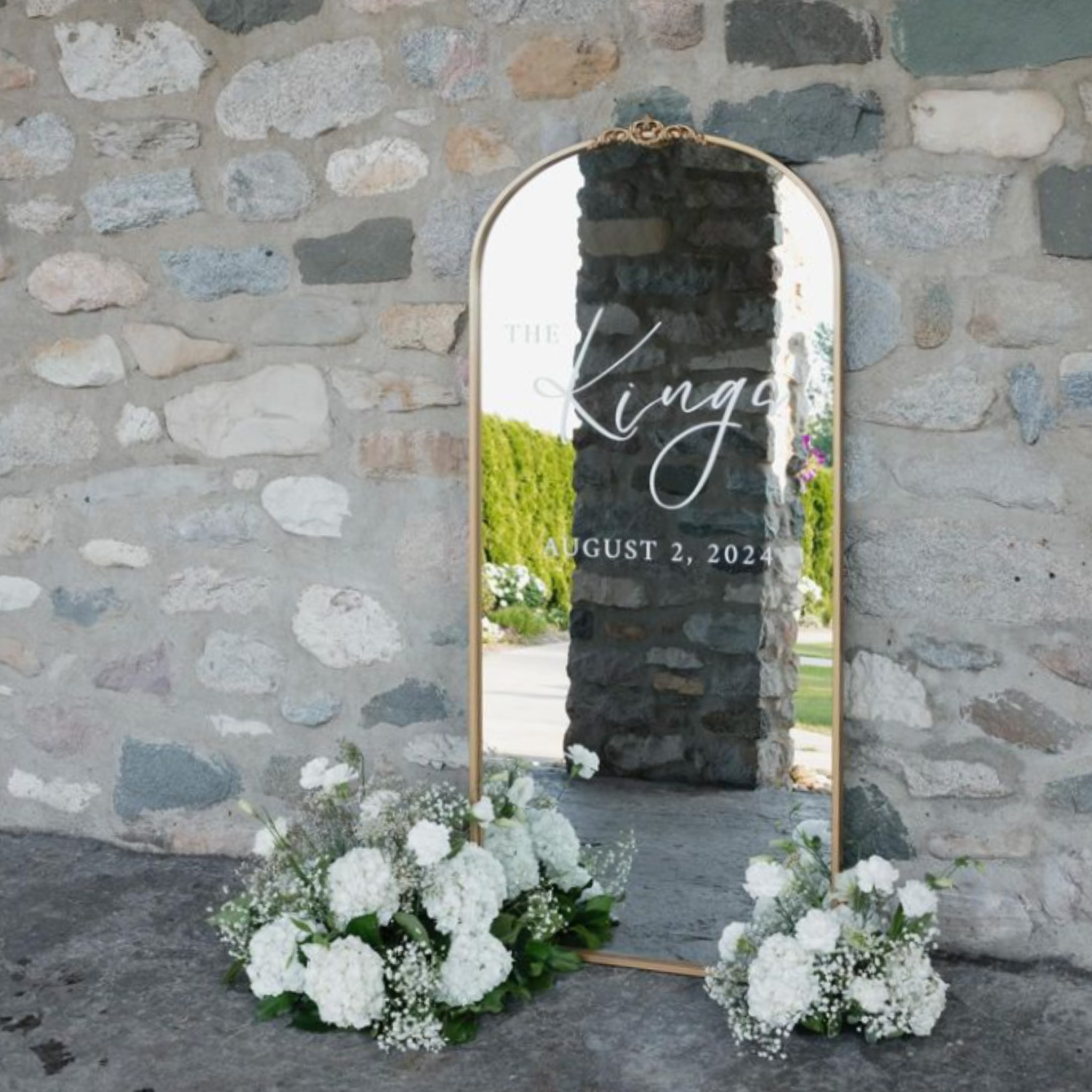 Large gold wedding welcome sign mirror with floral arrangement.